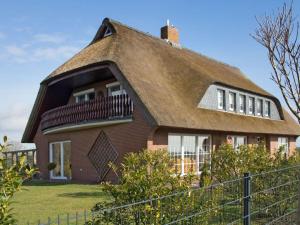 een groot huis met een rieten dak bij Holiday apartment reet domicile in Hage