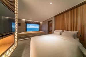 ein Schlafzimmer mit einem großen Bett und einem großen Fenster in der Unterkunft Yeonhwamun Hotel Yeongdeok in Yŏngdŏk