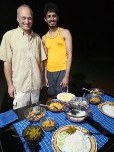 Dois homens à frente de uma mesa de comida. em Deer Garden Guest em Pollonaruva
