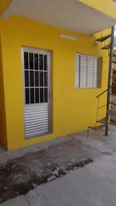 un edificio amarillo con una puerta y una escalera en Casa confortável! en Uruguaiana