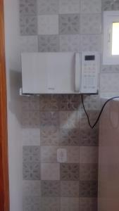 a microwave in a kitchen with a tile wall at Casa confortável! in Uruguaiana