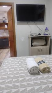 a bedroom with a bed with a flat screen tv on the wall at Casa confortável! in Uruguaiana