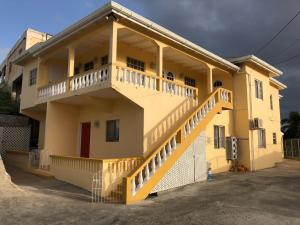 a yellow house with a balcony on the side of it at Patrickville in Calliste Land Settlement