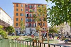 a tree in a park in front of a building at Hotel Riviera in Bastia