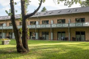 a large brick building with a tree in the foreground at Hotel garni "Zur Ostsee" - GM 69370 in Müritz