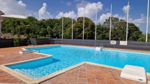 een groot zwembad met blauw water bij Le Goyave – Bel appartement cosy en résidence in Le Gosier
