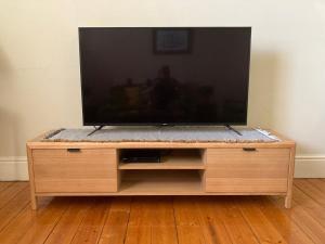 a flat screen tv sitting on a wooden entertainment center at Maeville Cottage in Broken Hill