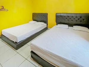 two twin beds in a room with a yellow wall at Penginapan Diar near Pantai Santolo RedPartner in Cilauteureun