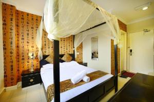 a bedroom with a canopy bed with white sheets at Seeds Hotel Shah Alam Section 7 in Shah Alam