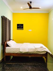 a bed in a room with a yellow wall at Yelagiri GoldHill Resort in Yelagiri