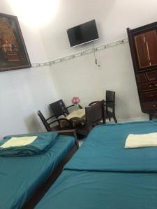 a room with two beds and a table and chairs at Khách Sạn Vinhomes Huỳnh Hotel in Ben Tre