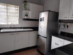 a kitchen with a refrigerator and a sink at The Rose Guesthouse in eMalahleni