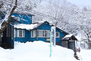 una casa azul con un cartel en la nieve en Luna House, en Nakano