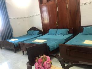 a room with two beds and a table with flowers at Khách Sạn Vinhomes Huỳnh Hotel in Ben Tre