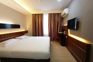 a hotel room with a bed and a television at OYO 90091 Hi Inn in Sibu
