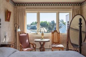 a bedroom with a bed and two chairs and a window at Martine Inn in Pacific Grove