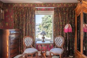 Zimmer mit 2 Stühlen, einem Tisch und einem Fenster in der Unterkunft Martine Inn in Pacific Grove