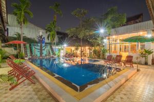 basen z leżakami i parasolami w nocy w obiekcie Lotus Bleu Guest House w mieście Phumĭ Ta Phŭl