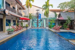basen w hotelu z krzesłami i parasolem w obiekcie Lotus Bleu Guest House w mieście Phumĭ Ta Phŭl
