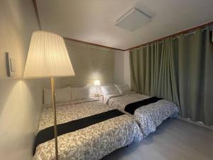 a bedroom with a bed with a lamp and a window at Hongdae Cozy in Seoul