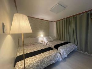 Un dormitorio con una cama con una lámpara y una ventana. en Hongdae Cozy, en Seúl