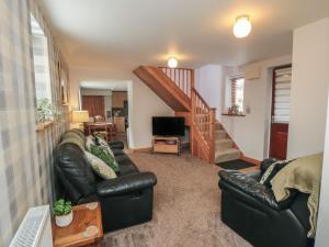 a living room with two leather couches and a staircase at Farm Yard Cottage in Pickering