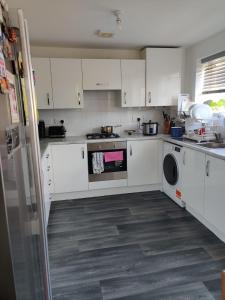 a kitchen with white cabinets and a dishwasher at Loving Home to Stay with Rear Garden and Patio in Rochdale