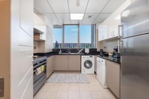 a large kitchen with a washer and dryer in it at Trinity Holiday Homes - Polo Residences Meydan in Dubai