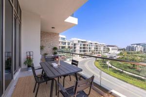 a table and chairs on a balcony with a view of a street at Trinity Holiday Homes - Polo Residences Meydan in Dubai