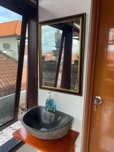 ein Badezimmer mit einem Steinwaschbecken und einem Spiegel in der Unterkunft Rodin Bali Hostel in Seminyak