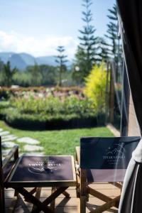 a table and chairs on a porch with a view of a garden at Thara Dara Khaoyai in Ban Tha Maprang