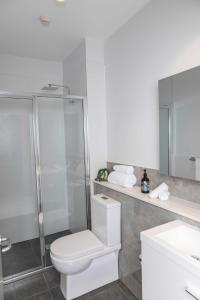 a bathroom with a toilet and a shower and a sink at Amica Serviced Apartments in Orange