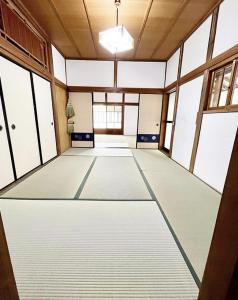 um grande quarto vazio com pisos e janelas brancas em さぬきリトリート 繋安芯堂 em Kawashima