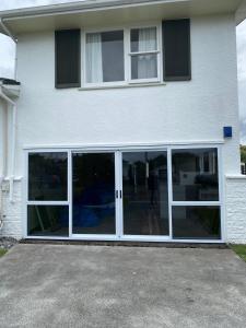 a white house with sliding glass doors on it at Birch Court - Tui in Whanganui