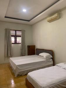 1 dormitorio con 2 camas y ventana en Homestay Mutiara, en Yogyakarta