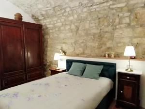 a bedroom with a bed and a stone wall at Iris nel Borgo in Greve in Chianti +12 photos