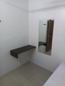 a bathroom with a mirror and a shelf on the wall at Majestic Inn in Trivandrum