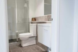 a white bathroom with a toilet and a shower at Amica Serviced Apartments in Orange