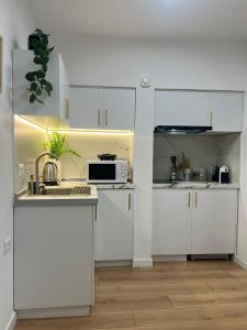 een witte keuken met een wastafel en een magnetron bij Bllok Scandi Urban Apartments 1 in Tirana