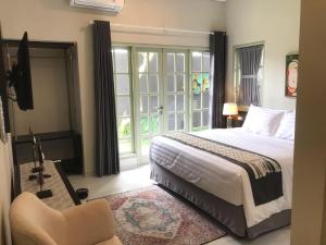 a bedroom with a bed and a chair and a window at Rumah Kenyeri in Denpasar