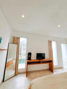 a bedroom with a tv and a desk with a mirror at Apple Villas & Apartments in Kerobokan