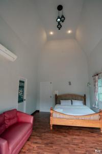 1 dormitorio con 1 cama y 1 sofá rojo en Suriyan Villa Erawan Kanchanaburi สุริยัน วิลล่า เอราวัณ กาญจนบุรี, en Tha Kradan