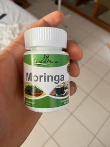 a hand holding a container of moringa medicines at Casa Johans in Piura