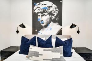 ein Schlafzimmer mit einem Bett mit blauen Kissen und einem Gemälde in der Unterkunft Paradise Palace Best Rooftop in HTX w Hot Tub in Houston