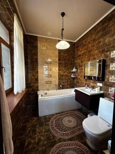 a bathroom with a tub and a toilet and a sink at Saule Guest House in Shymkent