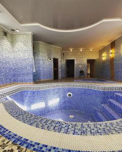 a large swimming pool with blue tiles in a building at Saule Guest House in Shymkent