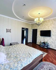 a bedroom with a bed and a flat screen tv at Saule Guest House in Shymkent