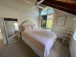 a bedroom with a large bed and a window at The Tree House Byron Bay in Byron Bay