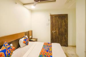 a bedroom with a bed with a wooden headboard and a door at FabHotel Krishna in Nagpur