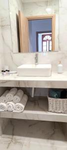 uma casa de banho com lavatório, espelho e toalhas em Apeiron Acropolis Suites em Atenas